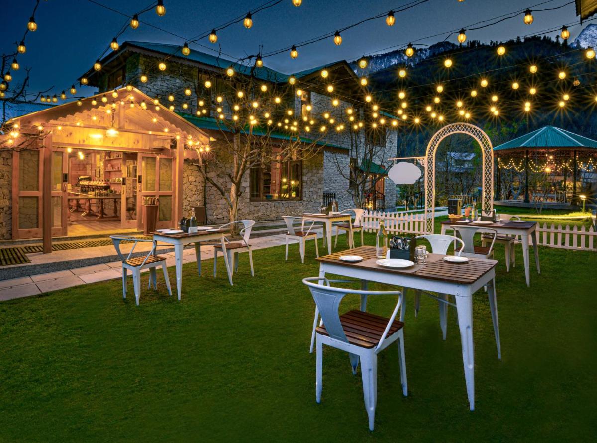 an outdoor patio with tables and chairs and lights at Storii By ITC Hotels Urvashis Retreat, Manali in Manāli an outdoor patio with tables and chairs and lights at Storii By ITC Hotels Urvashis Retreat, Manali in Manāli