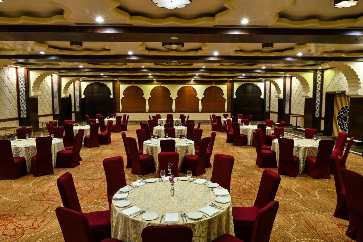a banquet hall with white tables and red chairs at Radisson Jodhpur in Jodhpur