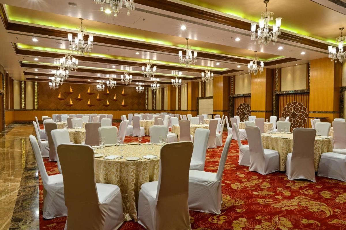 a banquet hall with white tables and chairs and chandeliers at Radisson Jodhpur in Jodhpur