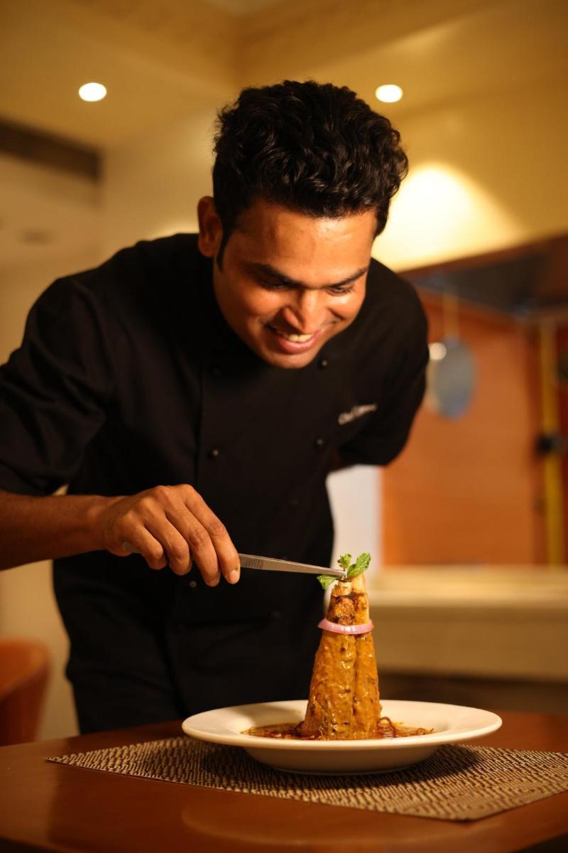 a man cutting into a piece of food on a plate at Holiday Inn Agra MG Road an IHG Hotel in Agra