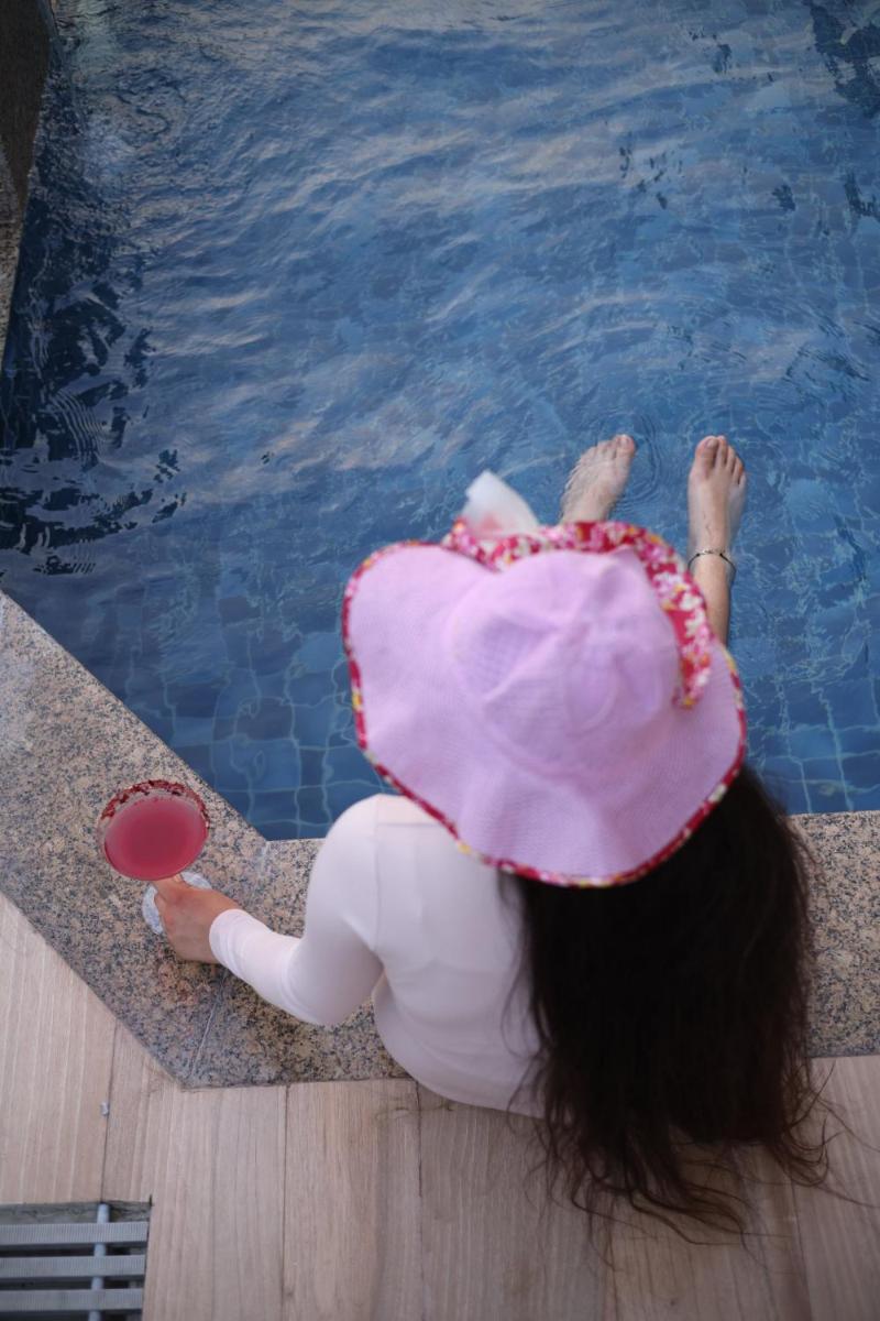 a girl in a pink hat sitting next to a swimming pool at Holiday Inn Agra MG Road an IHG Hotel in Agra