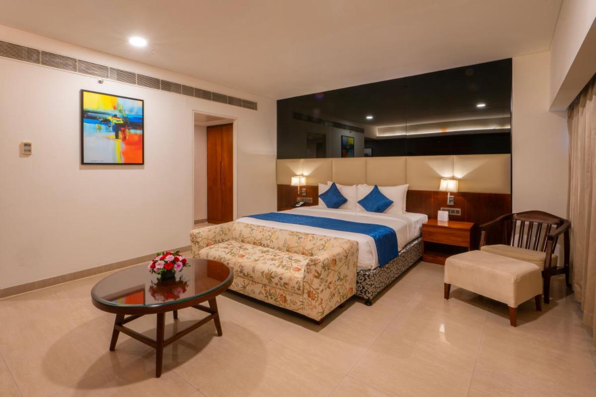 a bedroom with a bed and a couch and a table at The Raviz Calicut in Kozhikode