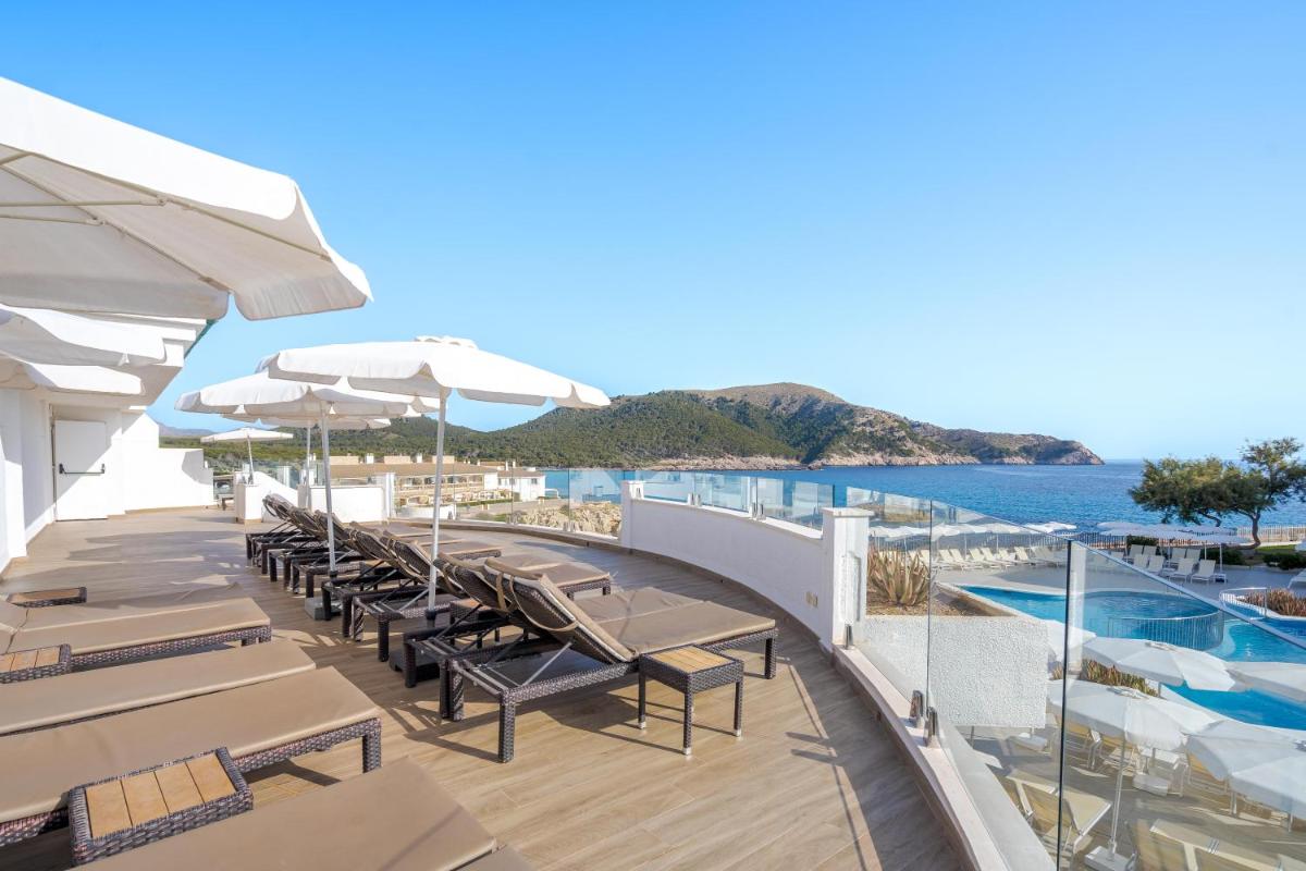 Una terraza con sillas y sombrillas y una piscina. en THB Guya Playa, en Cala Ratjada