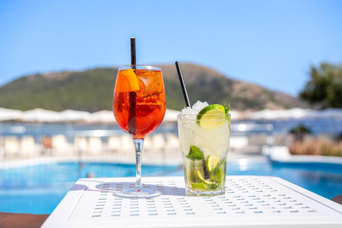 Dos cócteles sentados en una mesa junto a una piscina. en THB Guya Playa, en Cala Ratjada