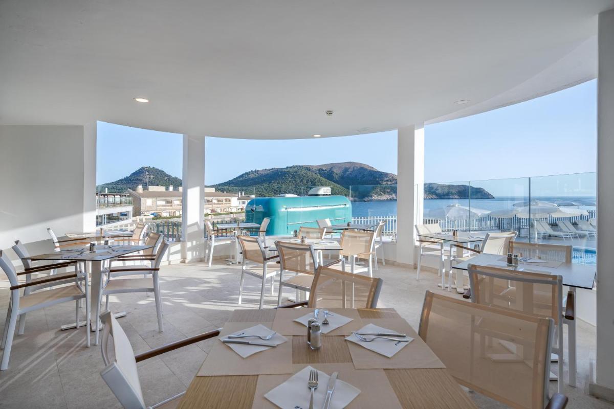 Un restaurante con mesas y sillas y vista al agua. en THB Guya Playa, en Cala Ratjada 48 fotos más