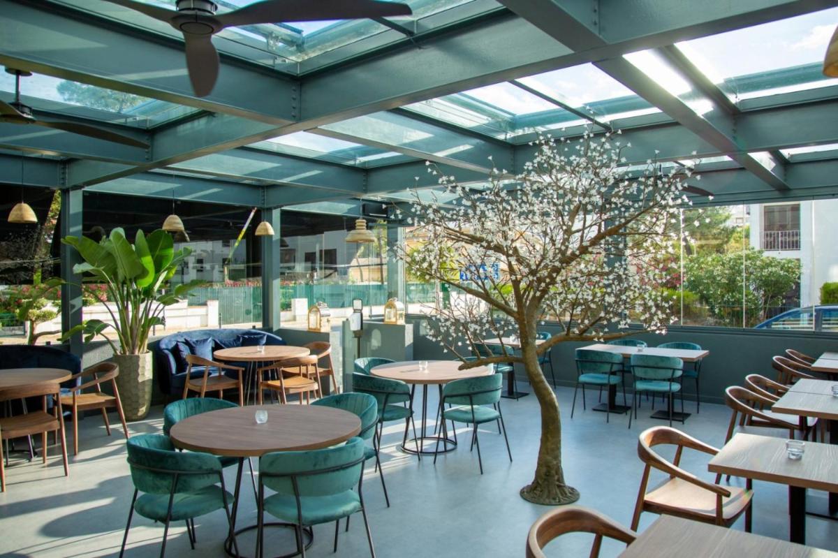 um restaurante com mesas, cadeiras e uma árvore em The Prime Energize Hotel & SPA - Algarve em Monte Gordo