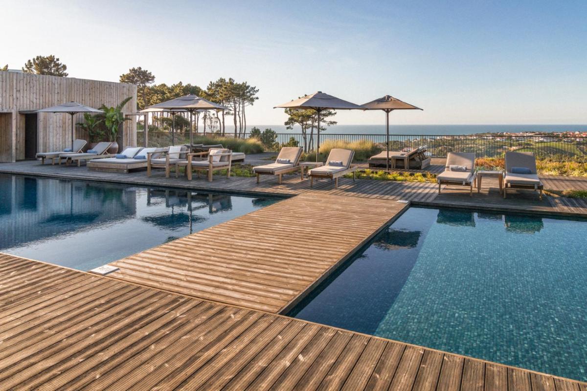 uma piscina com cadeiras e guarda-sóis numa casa em Immerso Hotel, a Member of Design Hotels na Ericeira