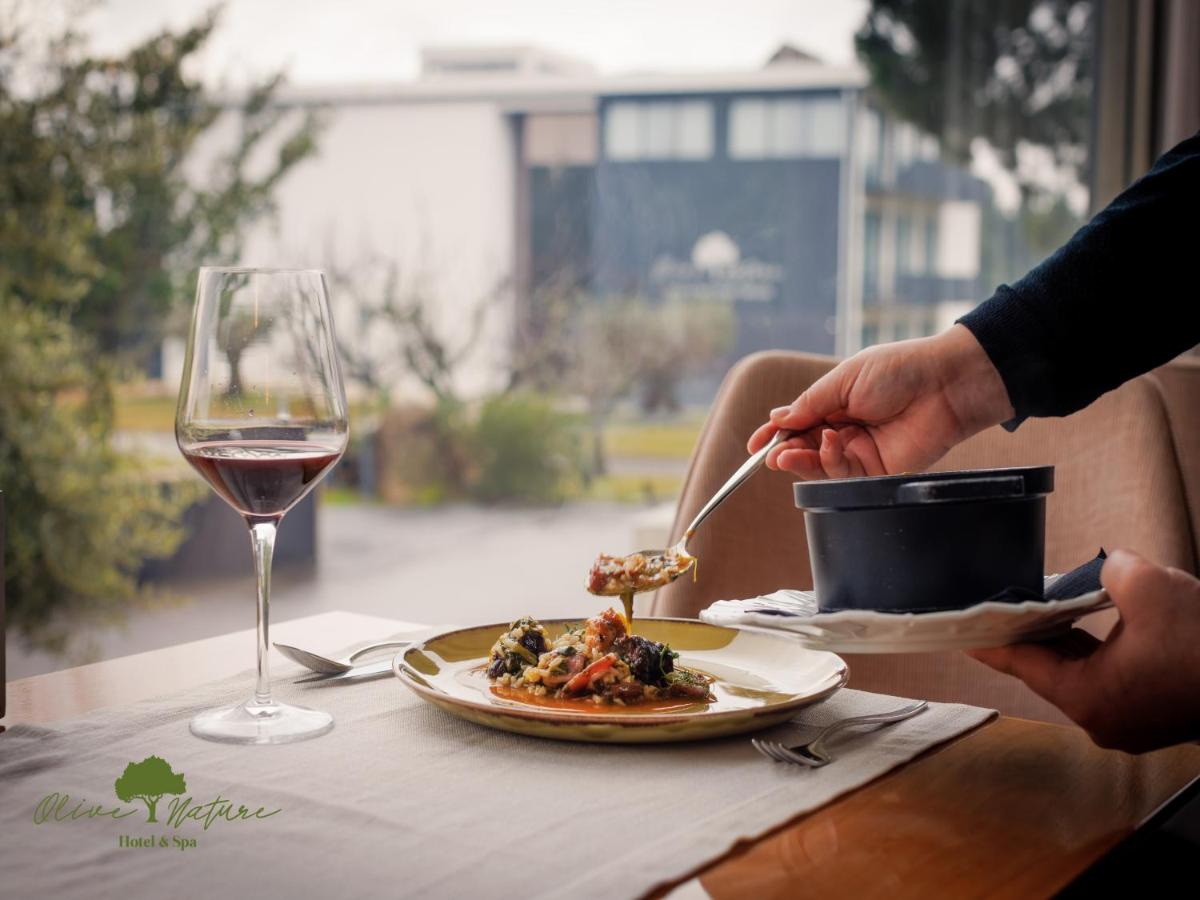 uma pessoa a comer comida numa mesa com um copo de vinho em Olive Nature Hotel & SPA - Quinta Valle de Passos em Valpaços