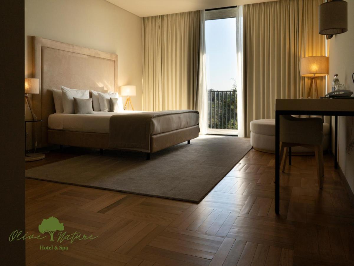 um quarto com uma cama, um sofá e uma janela em Olive Nature Hotel & SPA - Quinta Valle de Passos em Valpaços