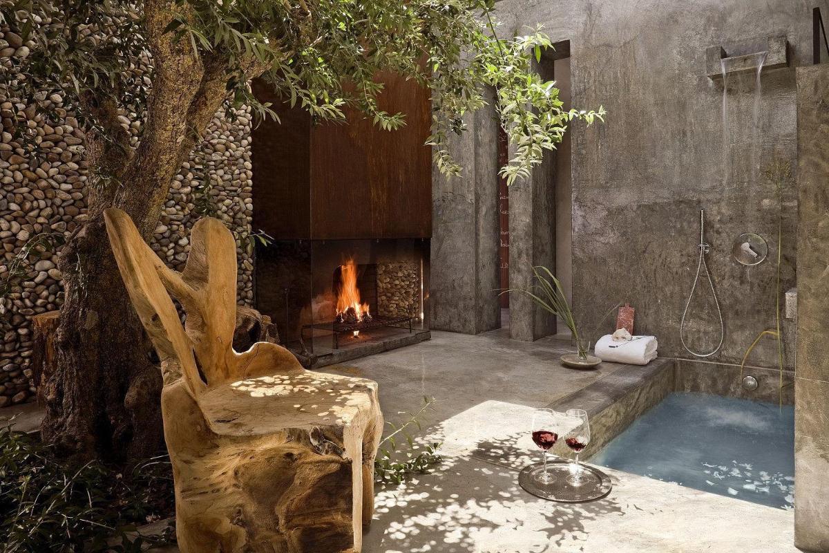 um banheiro com lareira, uma cadeira e uma banheira em Areias do Seixo Hotel em Santa Cruz