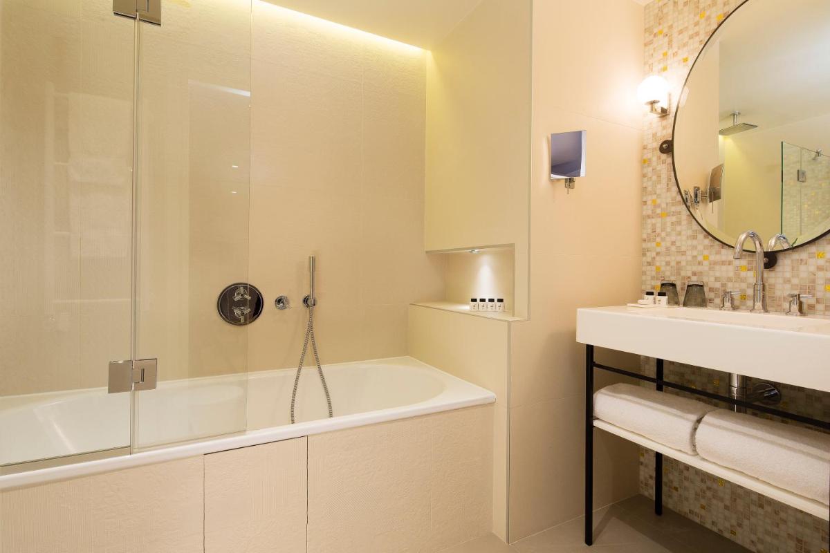 une salle de bain blanche avec une baignoire et un lavabo dans l'établissement Hotel & Spa La Belle Juliette, à Paris