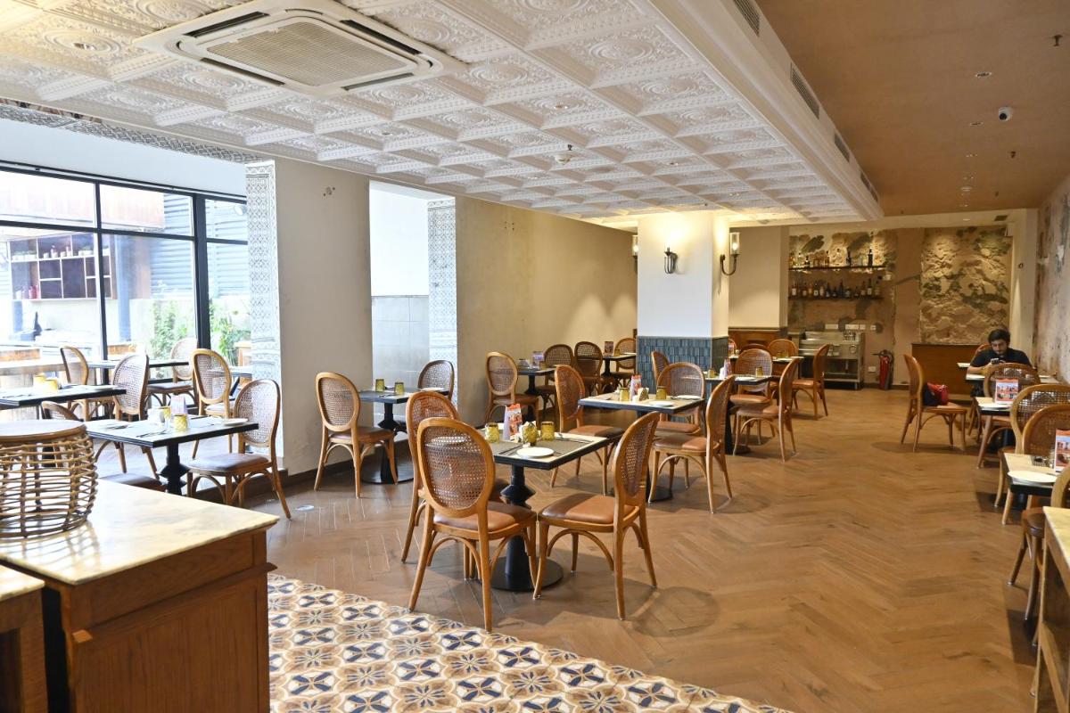 a restaurant with tables and chairs in a room at Zone Connect by The Park Saket New Delhi in New Delhi a restaurant with tables and chairs in a room at Zone Connect by The Park Saket New Delhi in New Delhi