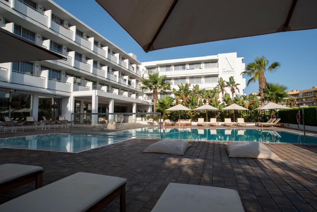 un hotel con una piscina con sombrillas y un edificio en Hotel Anfora Ibiza, en Es Canar