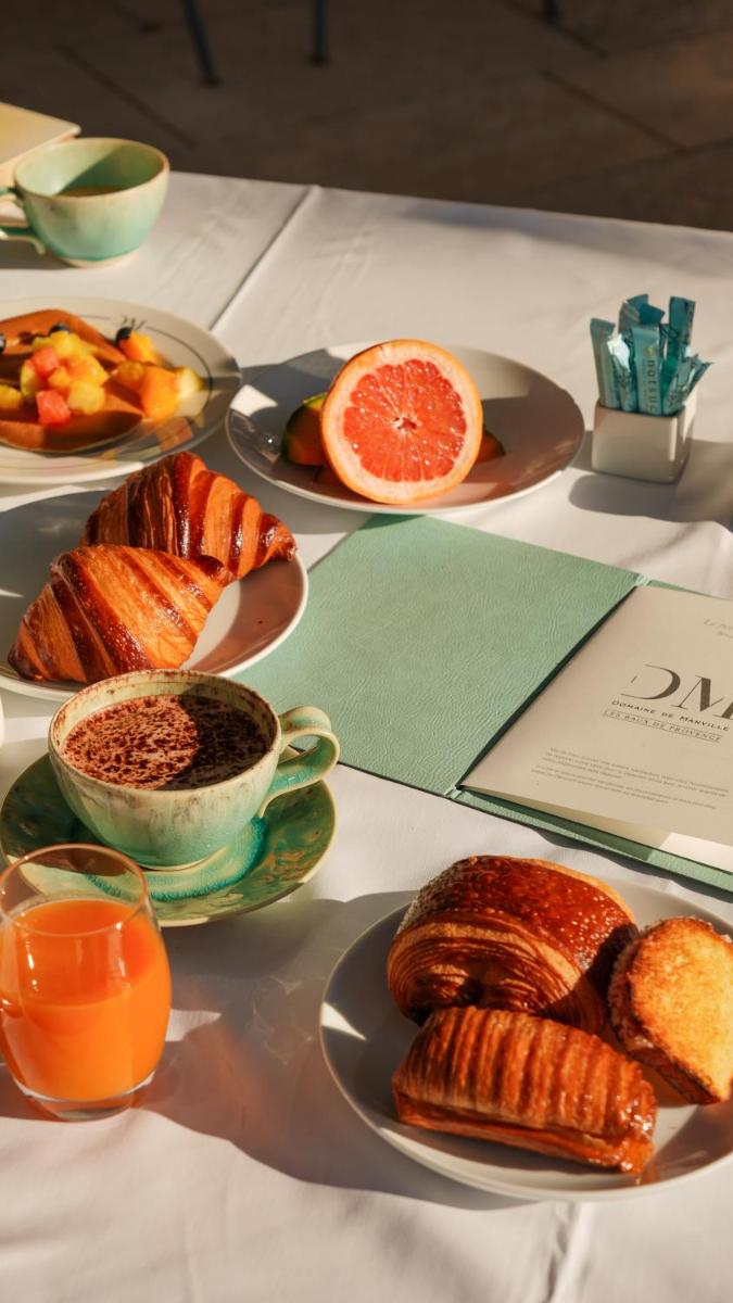 une table garnie d'assiettes de nourriture et de jus d'orange dans l'établissement Domaine De Manville, aux Baux-de-Provence