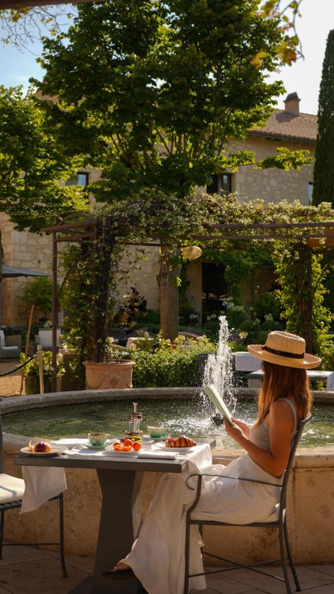une femme assise à une table devant une fontaine dans l'établissement Domaine De Manville, aux Baux-de-Provence