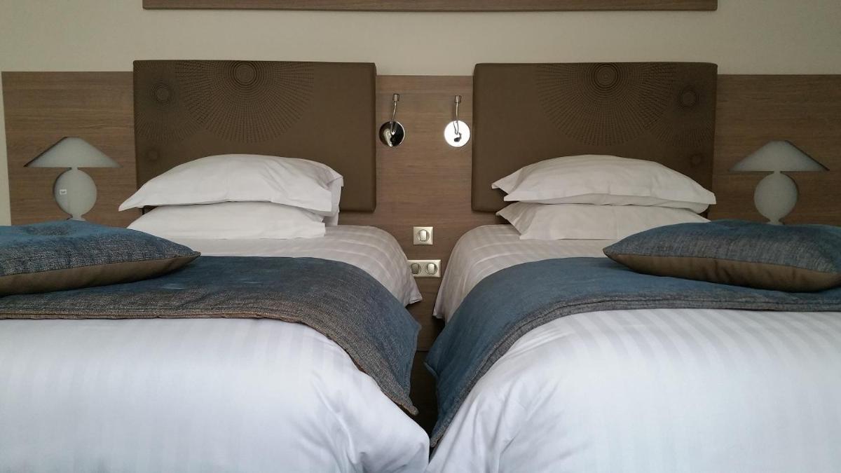 Un ou plusieurs lits dans un hébergement de l'établissement Brit Hotel de Grignan Vichy