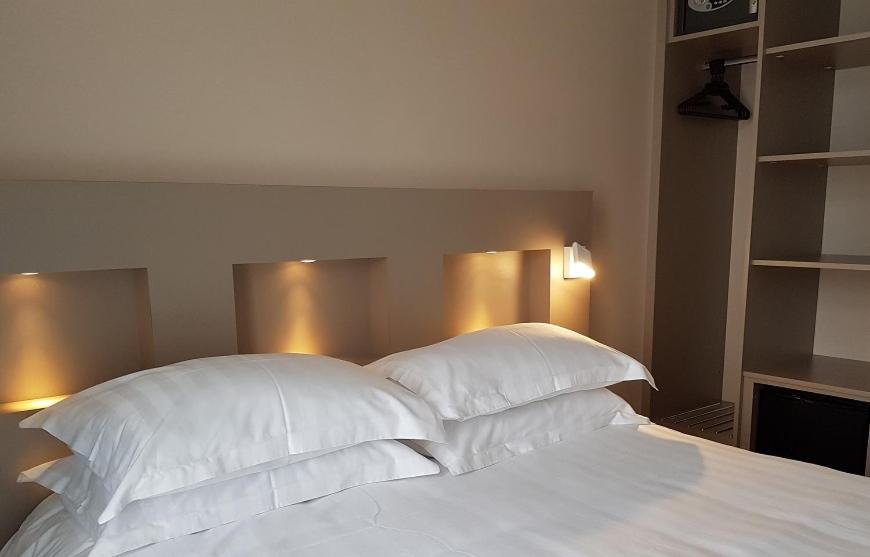 Un ou plusieurs lits dans un hébergement de l'établissement Brit Hotel de Grignan Vichy