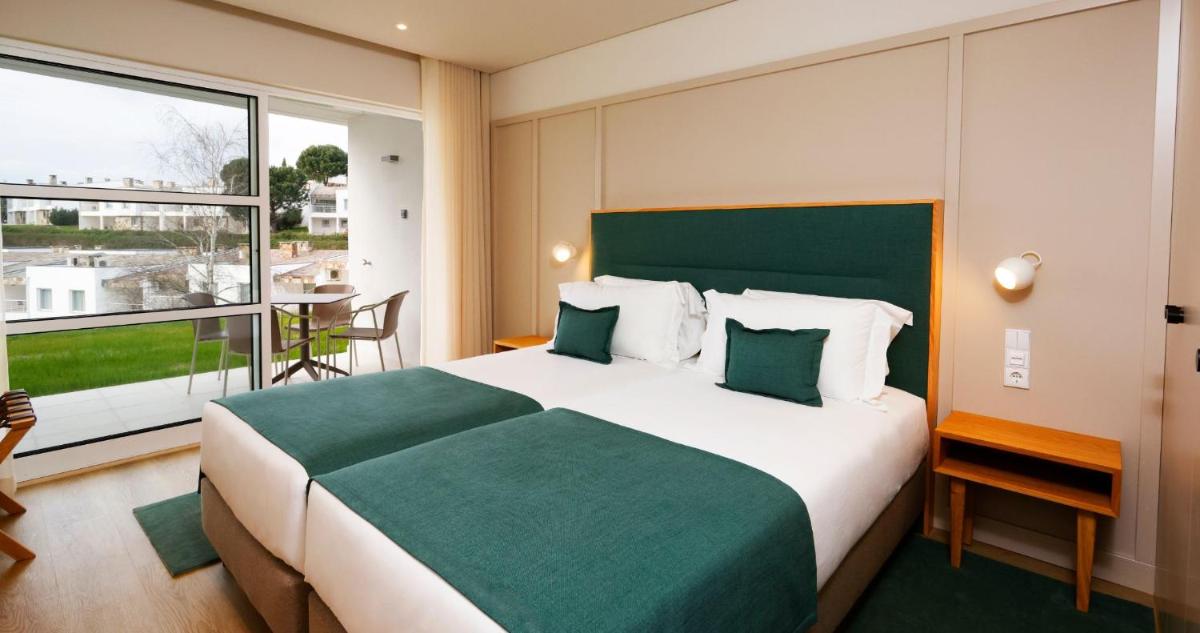 um quarto com uma cama grande e uma janela grande em Montebelo Aguieira Lake Resort & Spa em Mortágua
