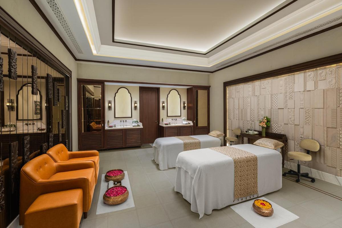 a hotel room with two beds and a chair at Pilibhit House, Haridwar – IHCL SeleQtions in Haridwār