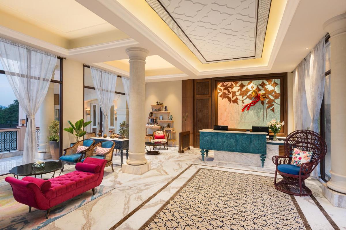 a living room with a red couch and a fireplace at Pilibhit House, Haridwar – IHCL SeleQtions in Haridwār