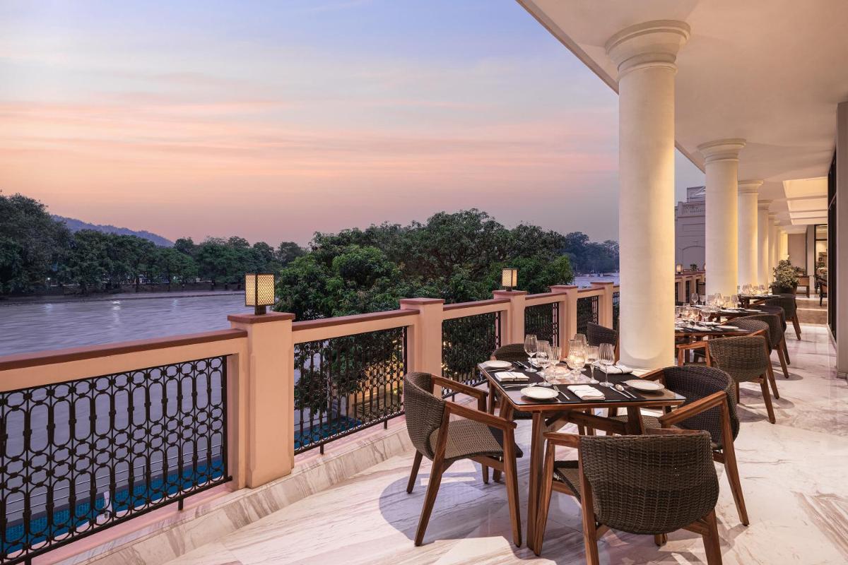 a balcony with tables and chairs with a view of a river at Pilibhit House, Haridwar – IHCL SeleQtions in Haridwār
