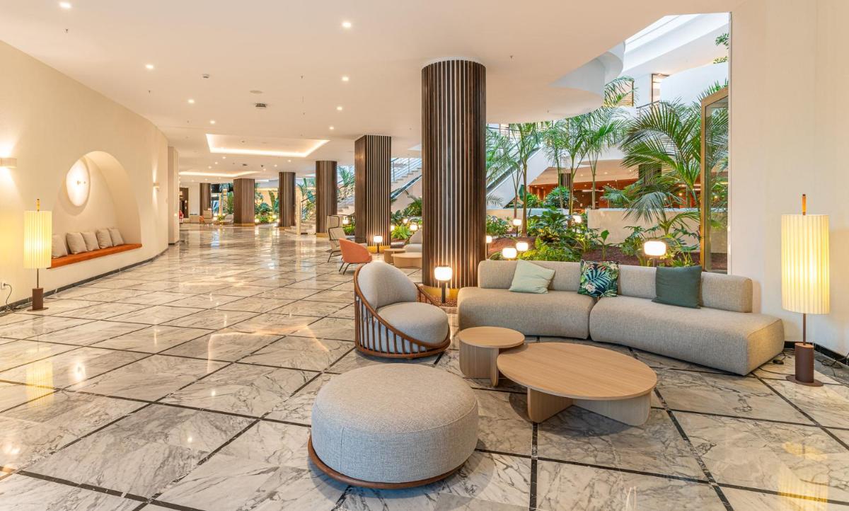 Un vestíbulo con un sofá, una mesa y sillas. en Mediterranean Palace, en Playa de las Américas