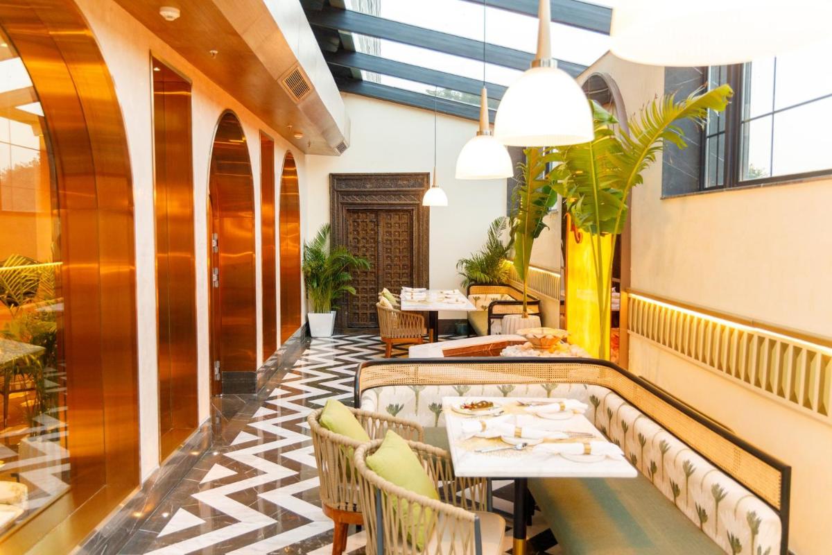 a restaurant with tables and chairs and plants at Crowne Plaza Today Gurugram by IHG in Gurgaon