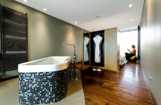 une salle de bain avec une baignoire et un homme assis dans une pièce dans l'établissement Le Petit Létraz, à Duingt