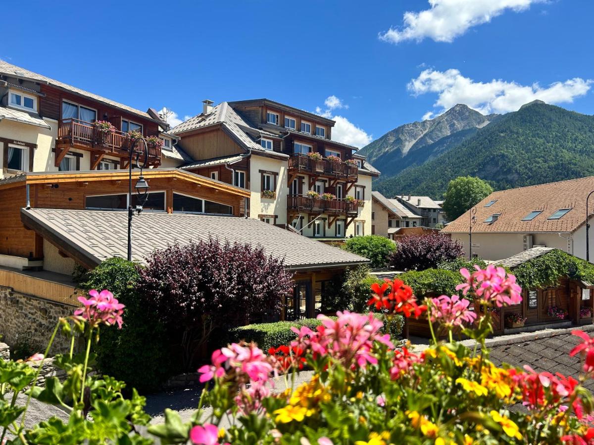 un groupe de bâtiments et de fleurs dans une ville dans l'établissement Logis Hôtel Les Autanes & Spa, à Ancelle