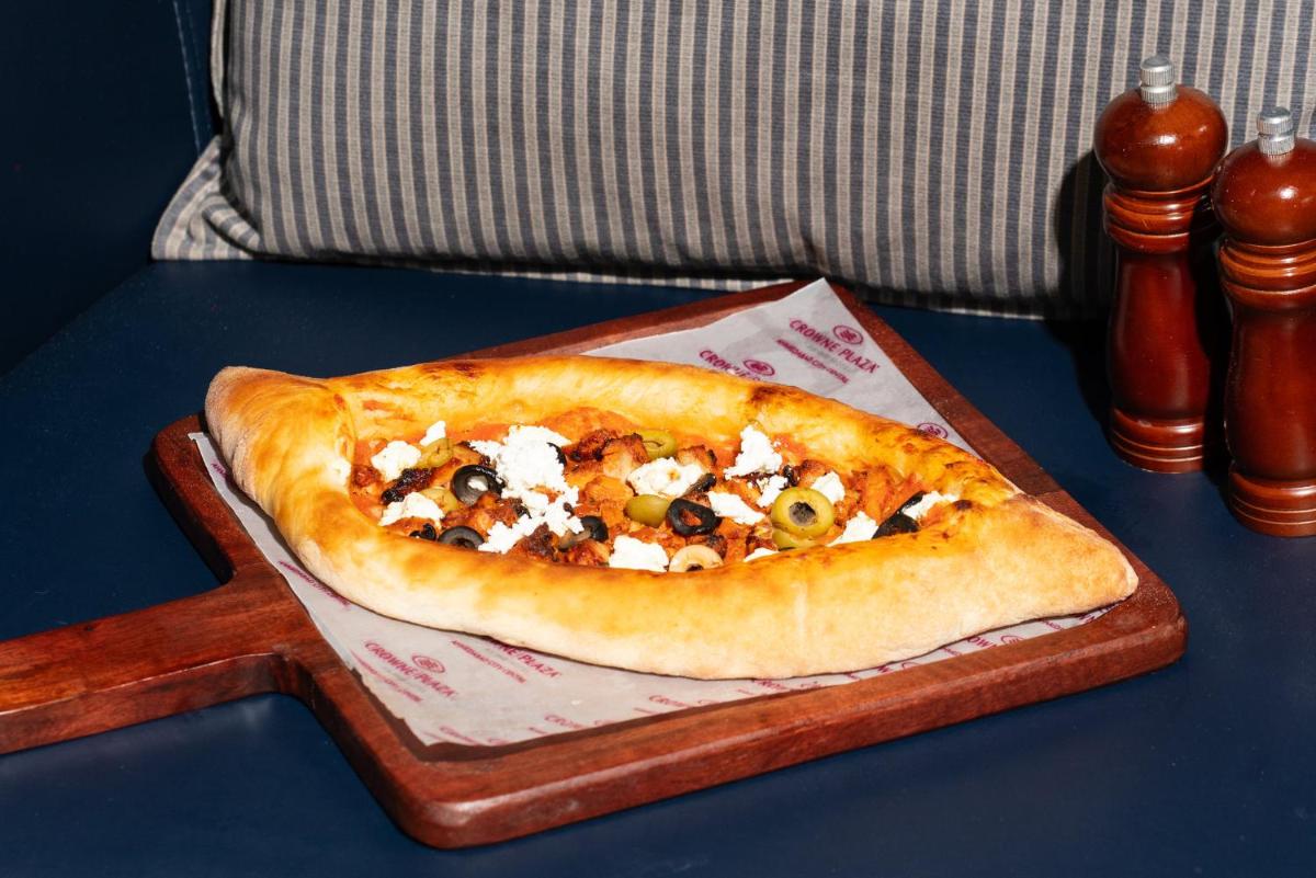 a pizza sitting on a plate on a table at Crowne Plaza Ahmedabad City Centre by IHG in Ahmedabad