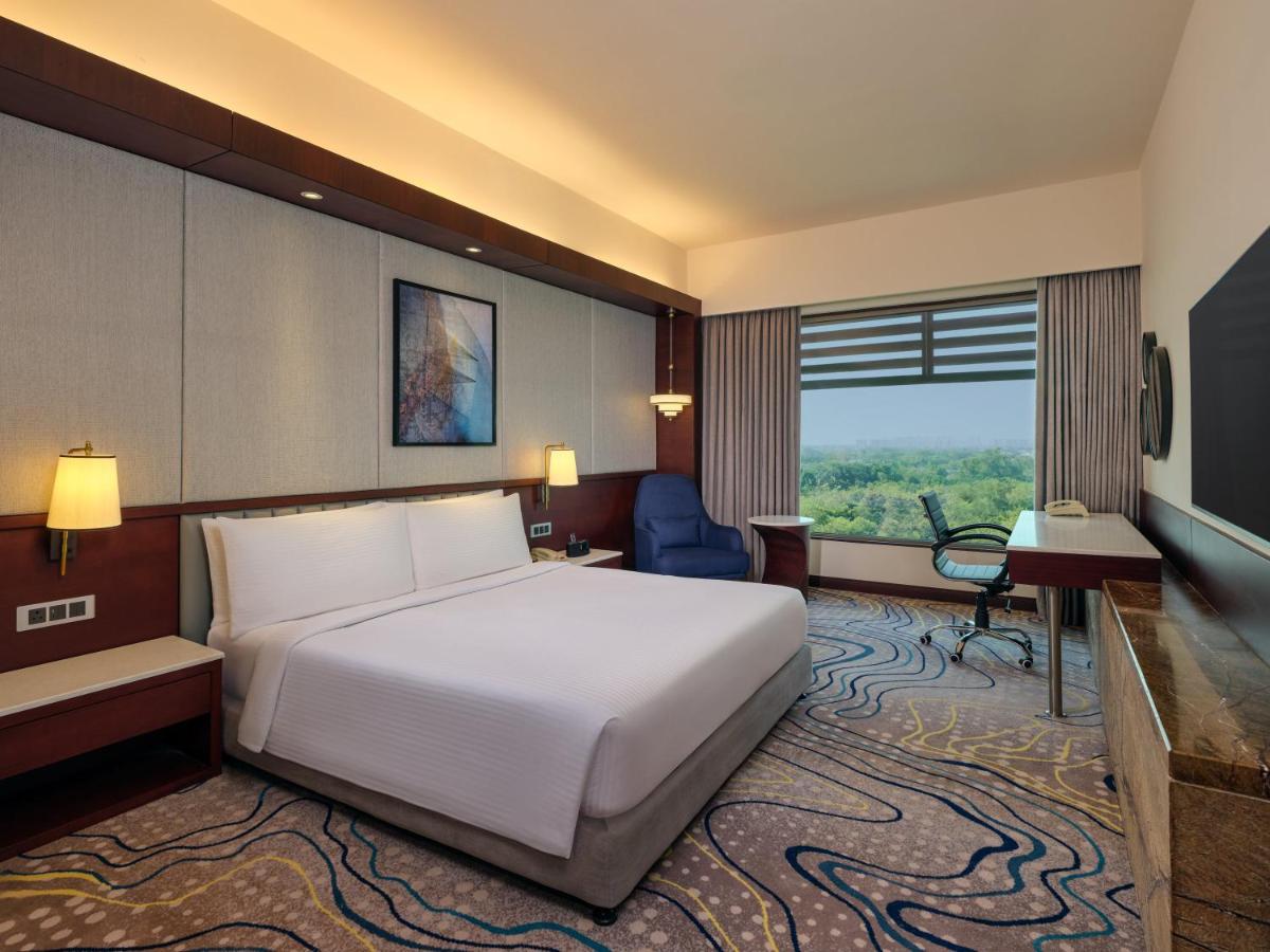 a hotel room with a large white bed and a desk at Crowne Plaza Ahmedabad City Centre by IHG in Ahmedabad