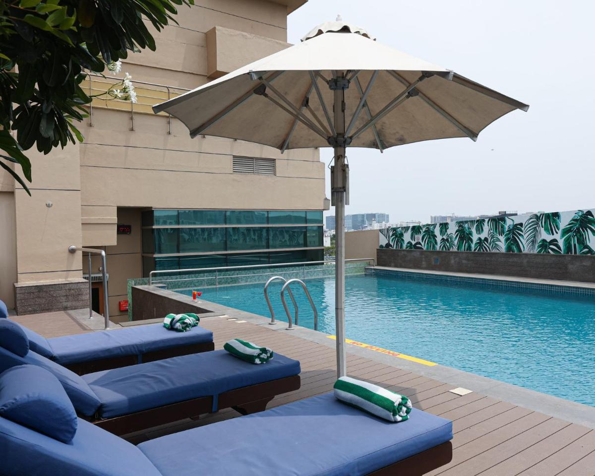 a pool with two blue chairs and an umbrella at Holiday Inn Chennai OMR IT Expressway by IHG in Chennai