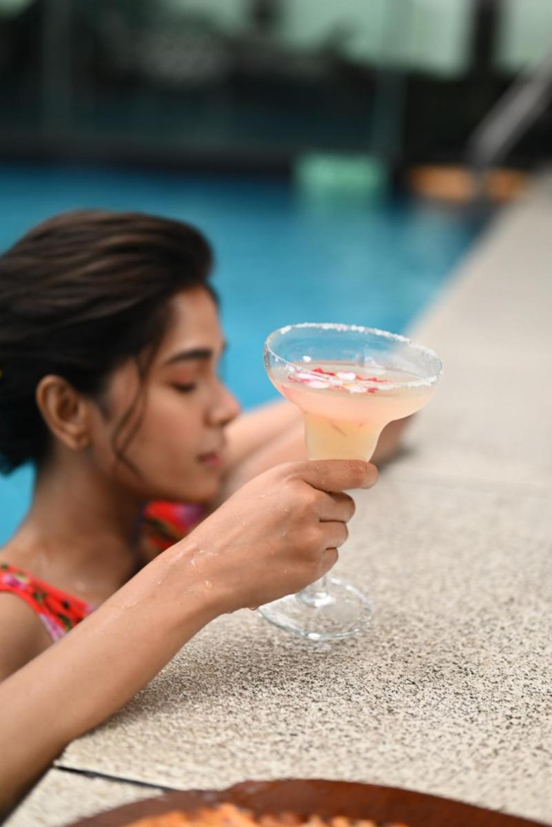 a woman holding a drink in front of a pool at The Park Kolkata in Kolkata