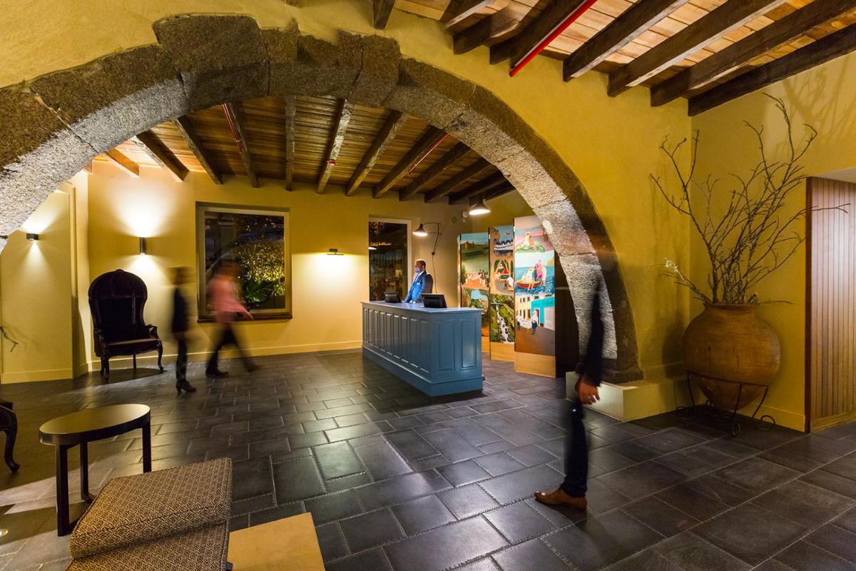 um lobby com uma arcada em um prédio com pessoas andando em Castanheiro Boutique Hotel no Funchal