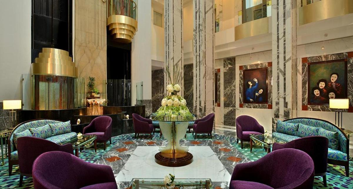 a lobby with purple chairs and a statue in the middle at Hotel Marine Plaza in Mumbai