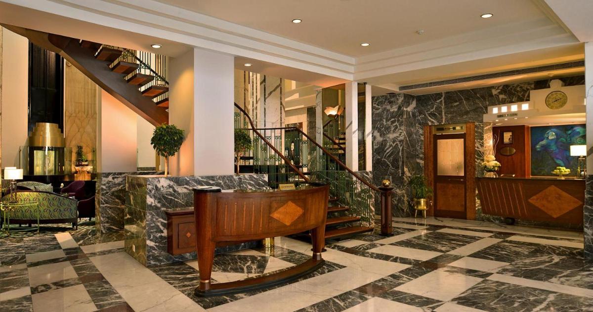 a lobby with a staircase and a piano at Hotel Marine Plaza in Mumbai