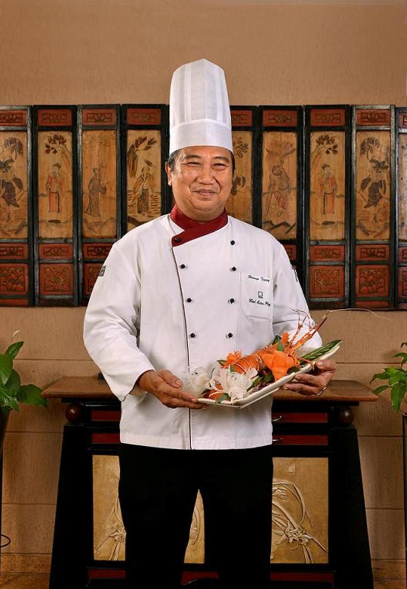 a man in a chefs hat holding a plate of food at Hotel Marine Plaza in Mumbai
