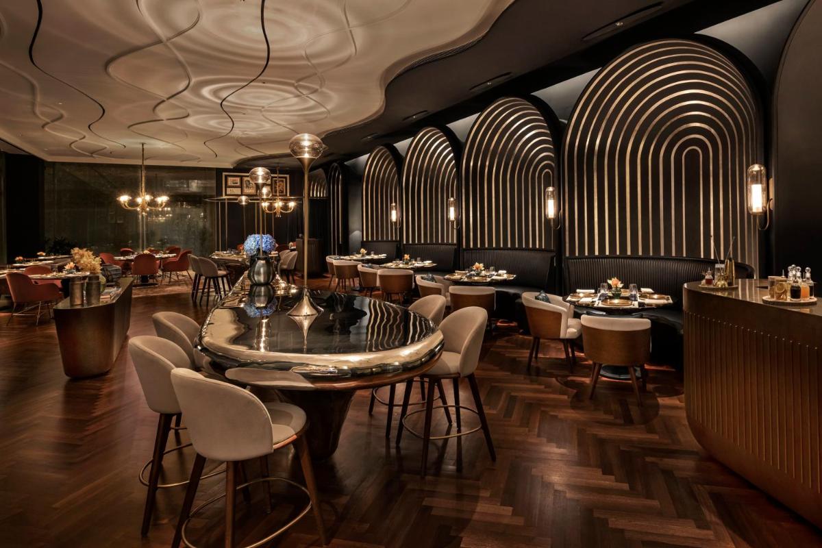 a restaurant with a table and chairs and a bar at The Oberoi Gurgaon in Gurgaon