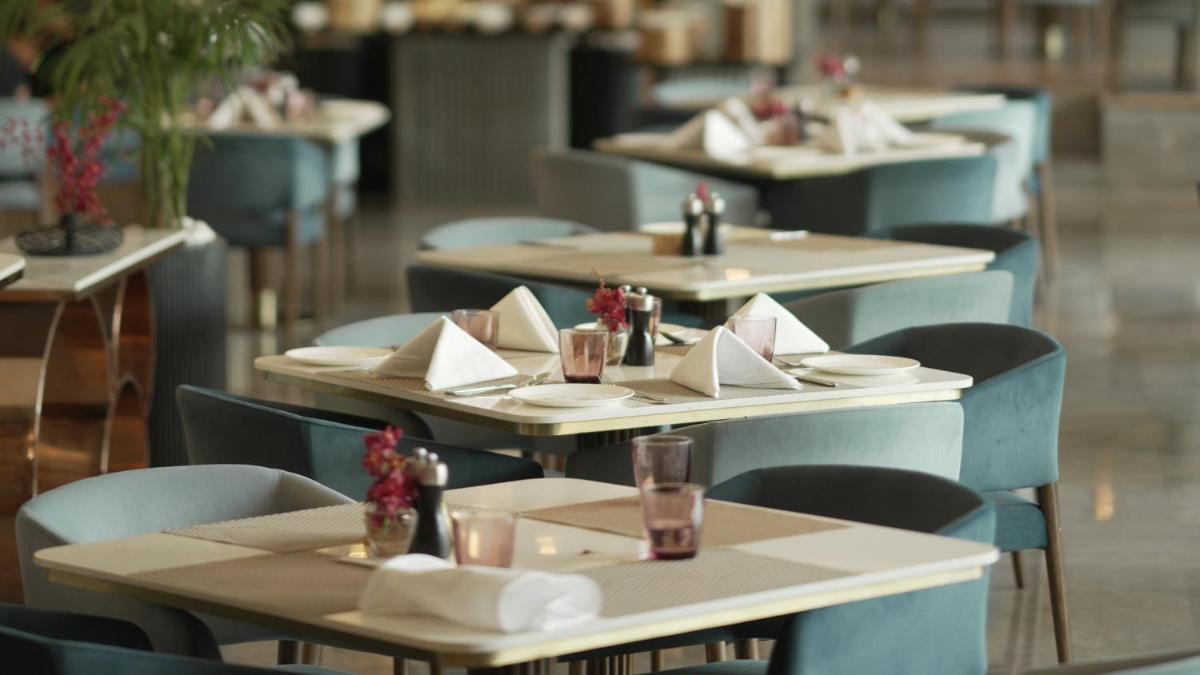 a row of tables and chairs with plates and napkins at Crowne Plaza Today Gurugram by IHG in Gurgaon