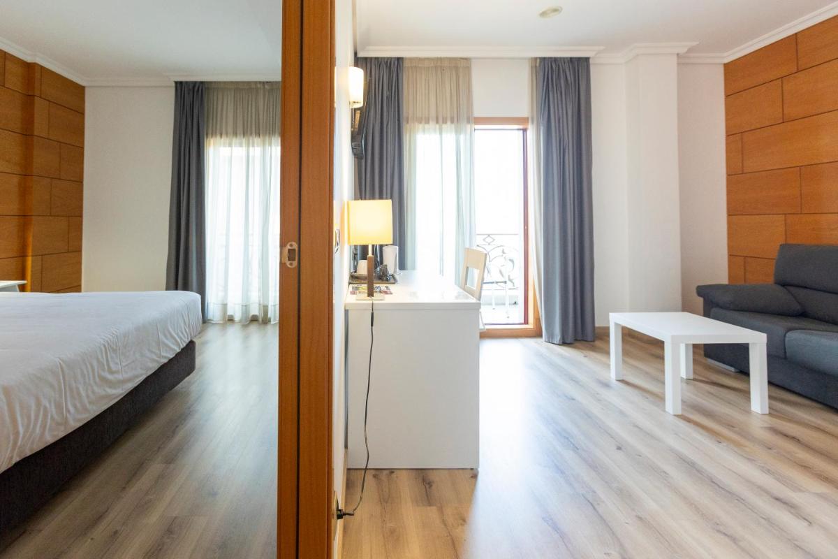 una habitación de hotel con una cama y un sofá en Hotel Alfonso I, en Tui