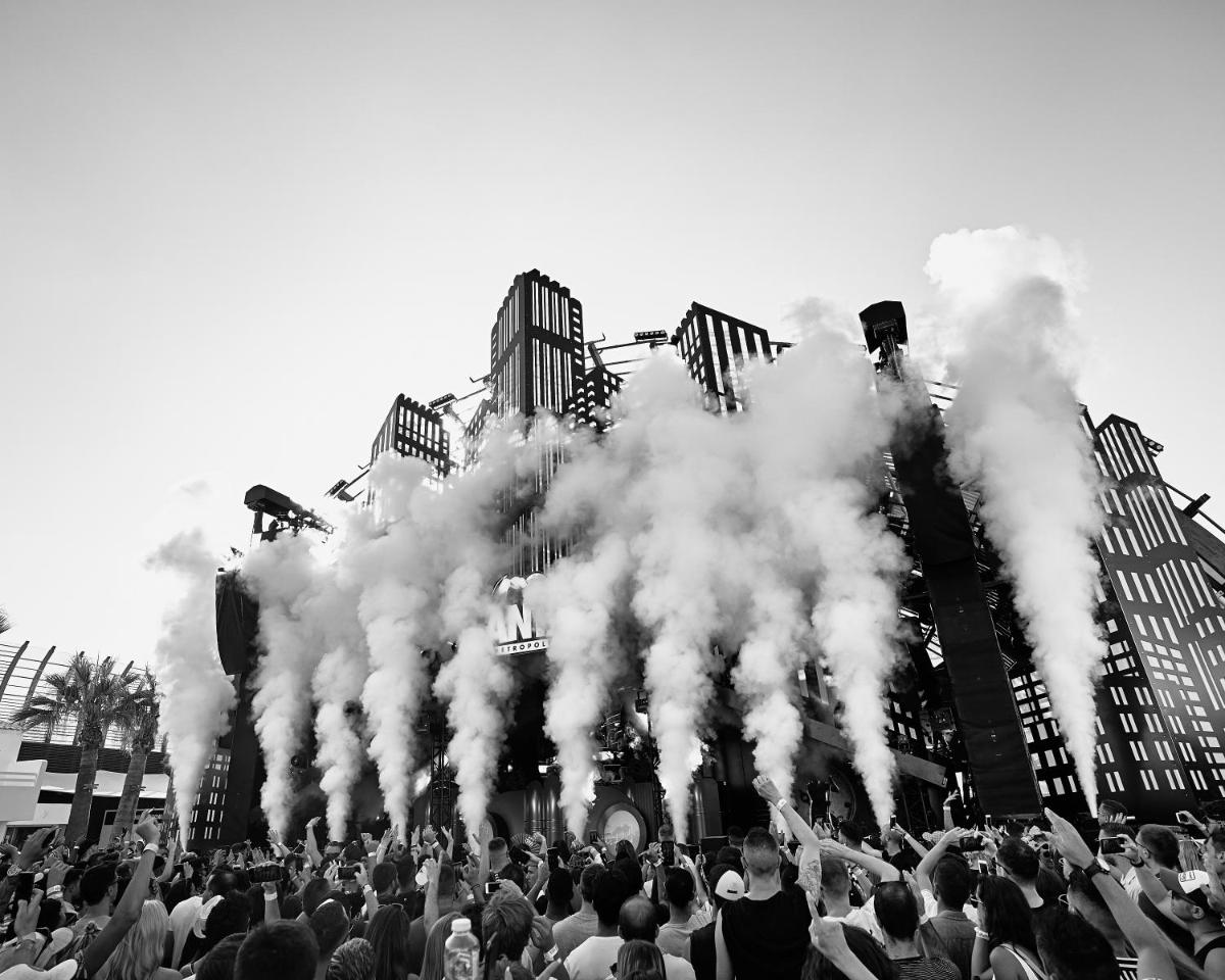 una multitud de gente parada frente a un edificio con humo en Ushuaïa Ibiza Beach Hotel - Adults Only - Club Entrance Included, en Playa d'en Bossa