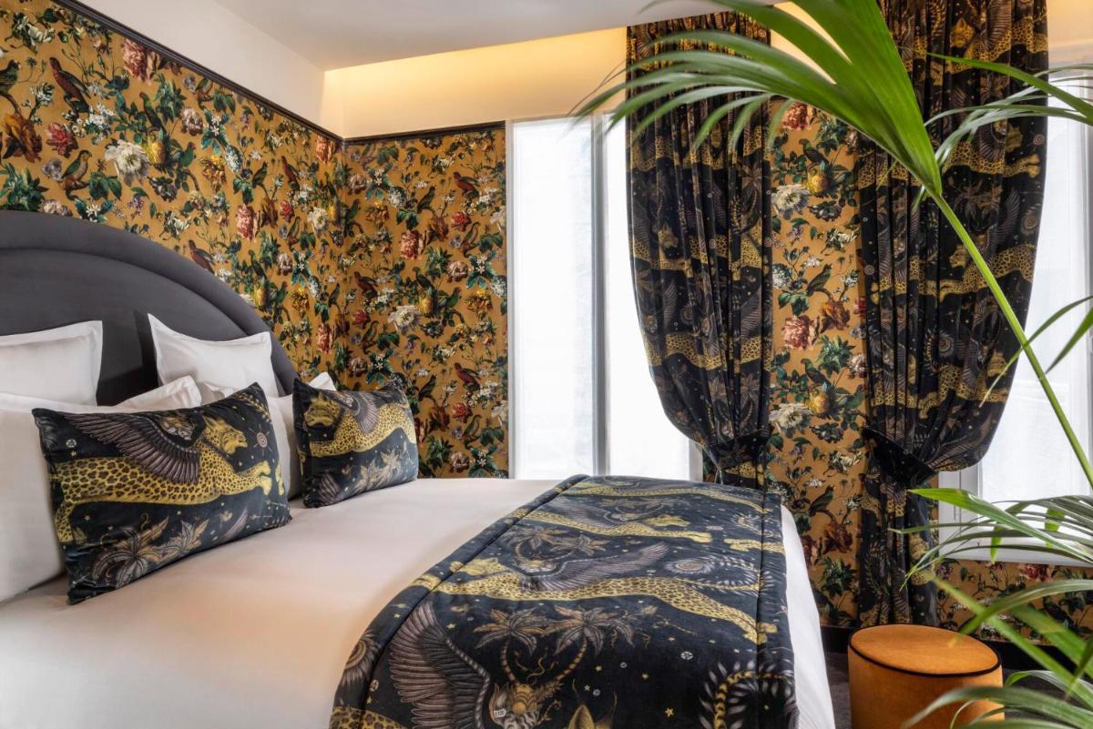 - une chambre avec un lit et du papier peint floral dans l'établissement Hôtel Ginette à la Folie & Spa, à Paris