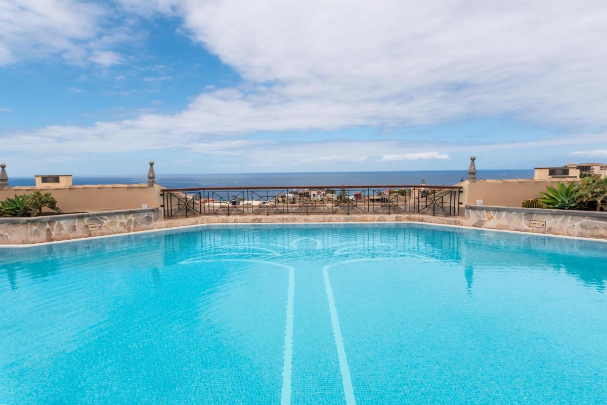 Una gran piscina azul con el océano al fondo. en GF GRAN COSTA ADEJE*****, en Adeje