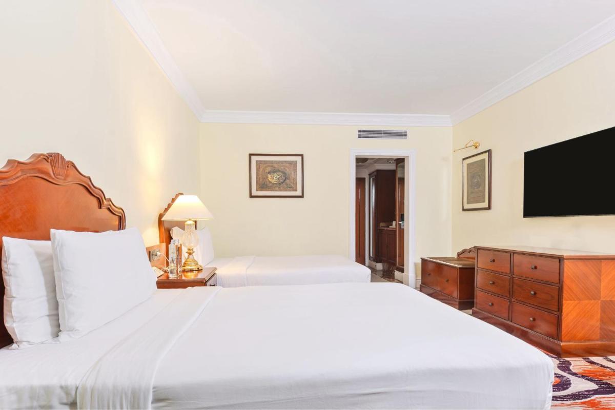 a bedroom with two beds and a flat screen tv at Le Royal Meridien Chennai in Chennai