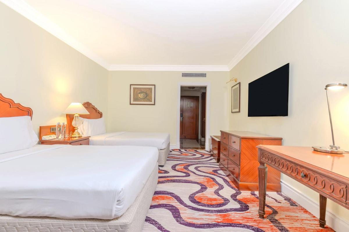 a hotel room with a bed and a tv at Le Royal Meridien Chennai in Chennai