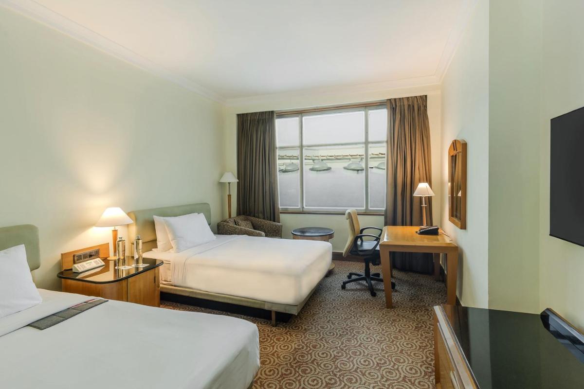 a hotel room with two beds and a desk at Le Royal Meridien Chennai in Chennai