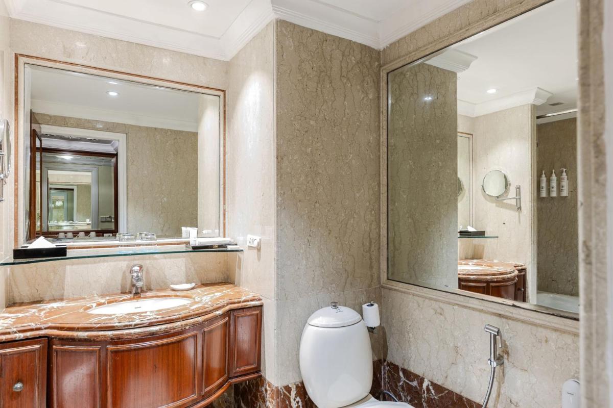 a bathroom with a sink and a mirror and a toilet at Le Royal Meridien Chennai in Chennai