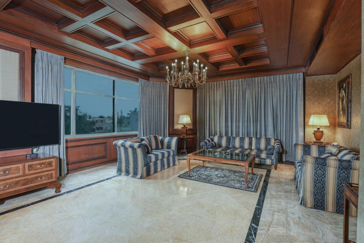 a living room with two chairs and a flat screen tv at Le Royal Meridien Chennai in Chennai