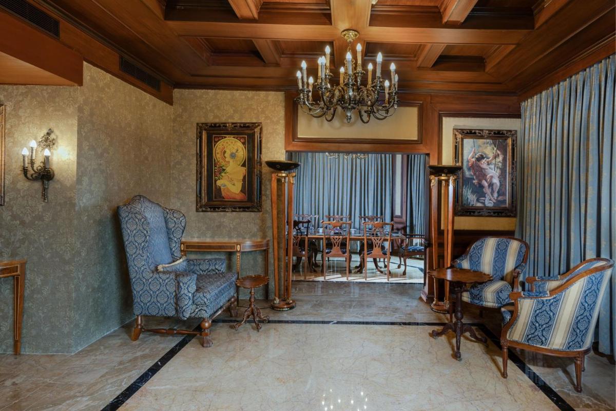 a living room with a chandelier and chairs and a table at Le Royal Meridien Chennai in Chennai