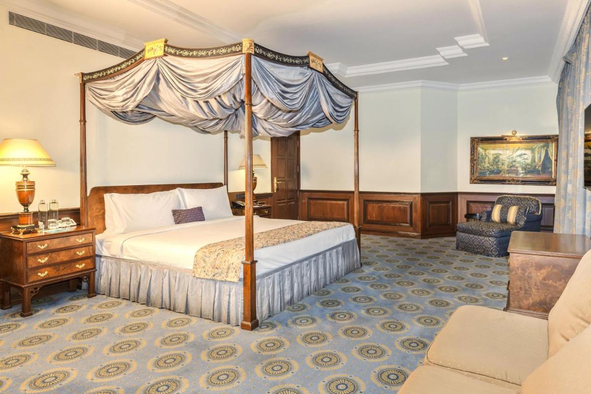 a bedroom with a canopy bed and a chair at Le Royal Meridien Chennai in Chennai
